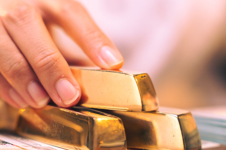 The hand holding the precious gold bar shows the success of the finance business and the economy of investment, the symbol and target of the treasure wealthy and the perfect millionaire concept.