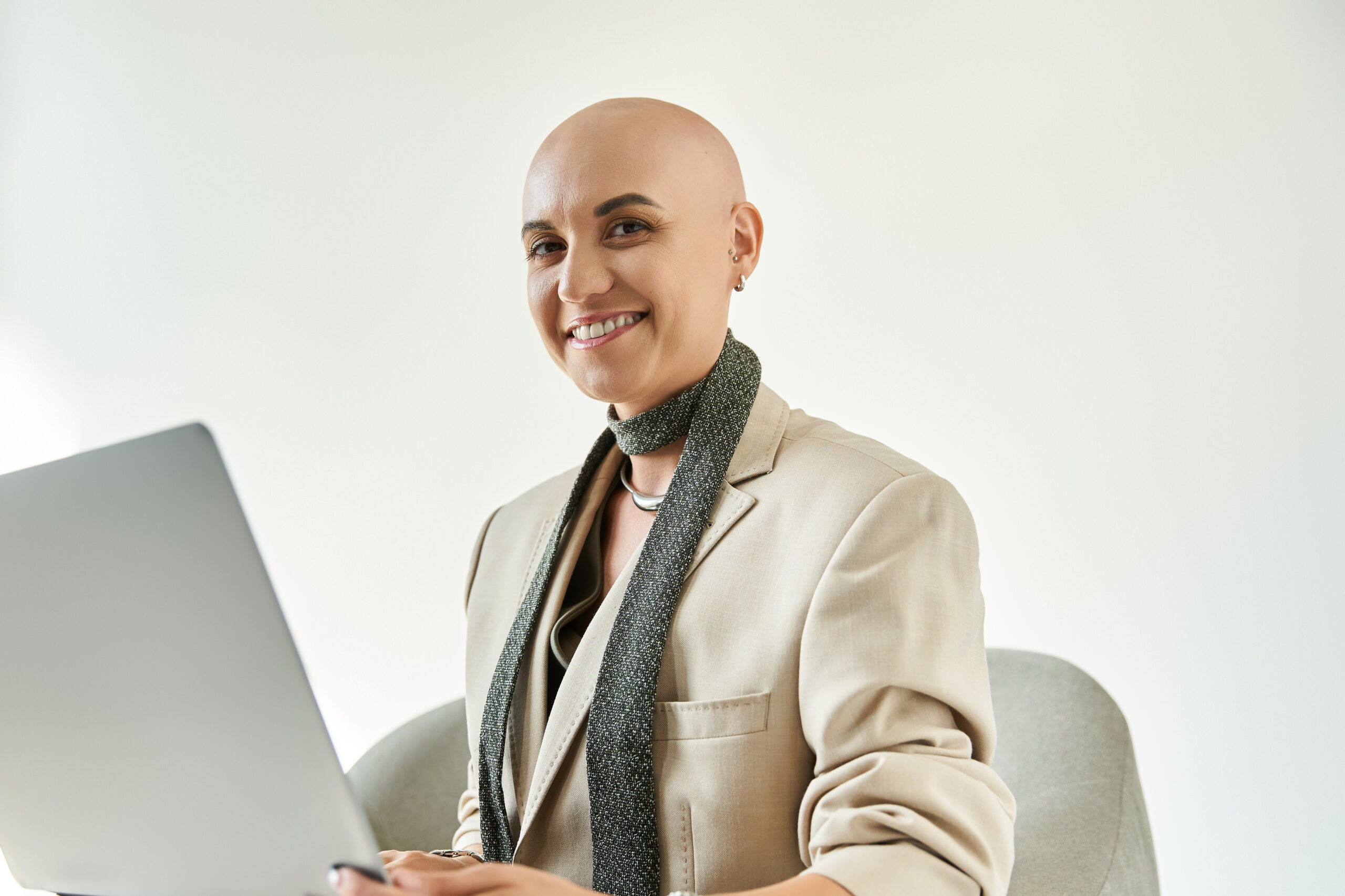 A confident young bald woman with alopecia is engaged in work at a stylish office desk.