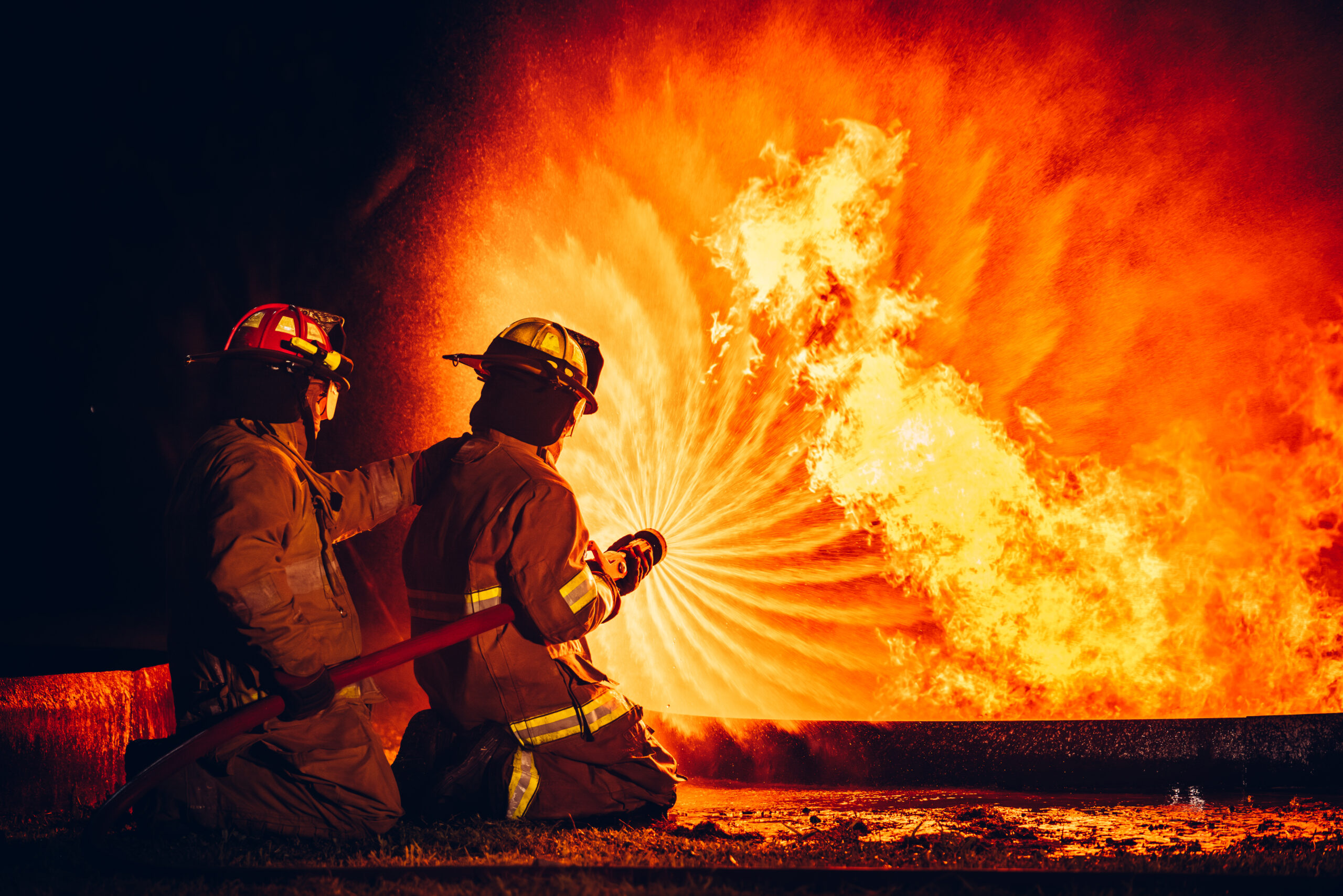 Fearless Firefighters Battling Blaze with Water and Extinguishers. Firefighters in Action, Extinguishing Fire with Teamwork and Courage. Intense Firefighting Training Exercise.